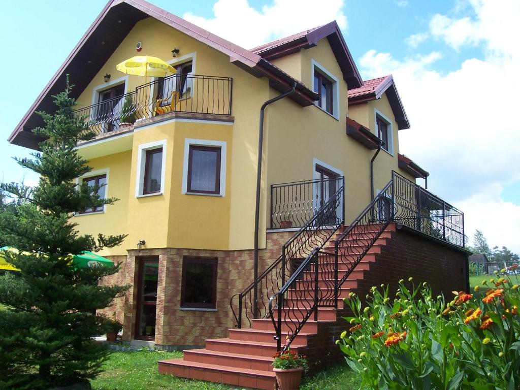 una casa amarilla con escaleras delante en Gosciniec Nad Stawem en Szczytno