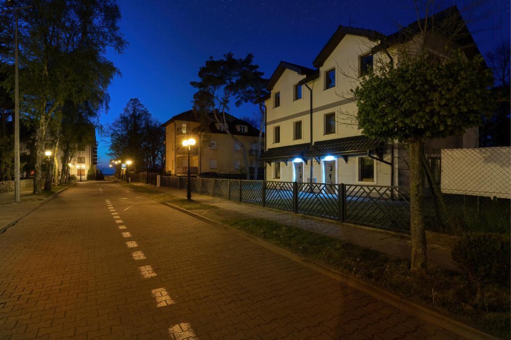 an empty street at night with houses and lights at Apartamenty Krakowska in Niechorze