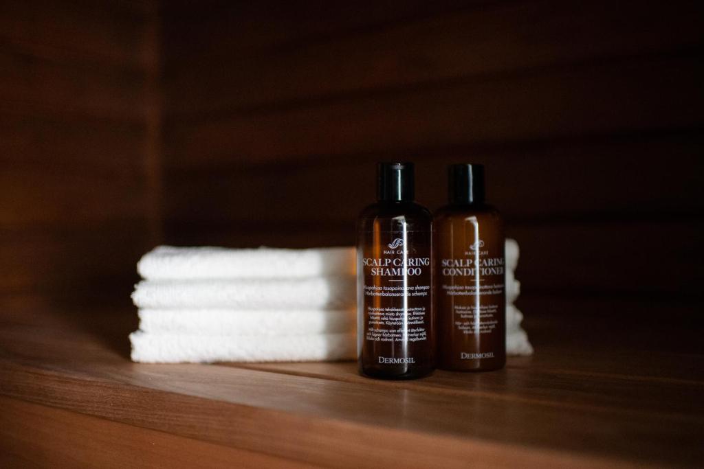 due bottiglie di shampoo accanto a un mucchio di asciugamani di Kesäelo a Porvoo
