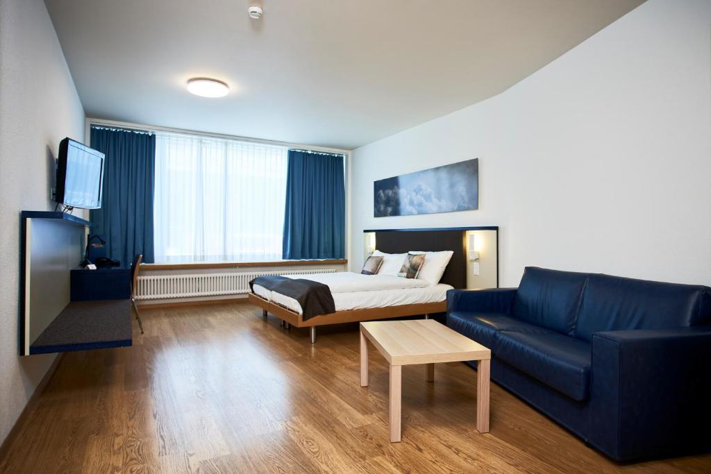a hotel room with a bed and a couch and a tv at Hotel Bristol Zurich in Zurich