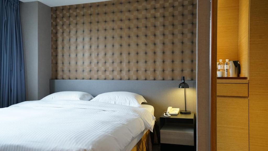 um quarto com uma grande cama branca e uma janela em City Suites - Taoyuan Gateway em Dayuan