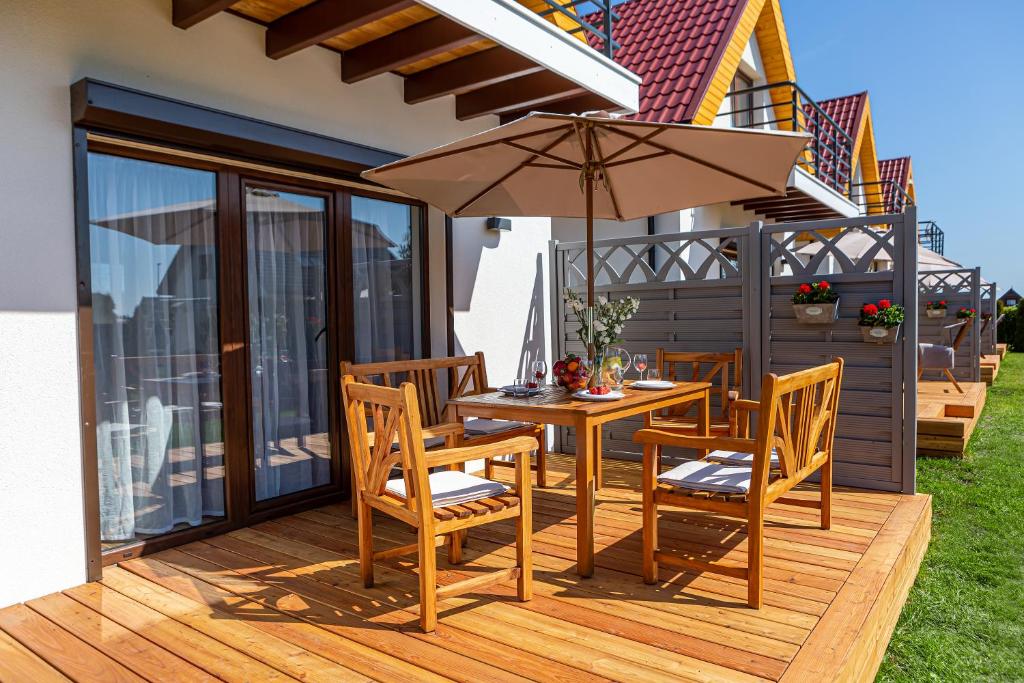 a wooden deck with a table and chairs and an umbrella at Domki wakacyjne 4 YOU in Ustka