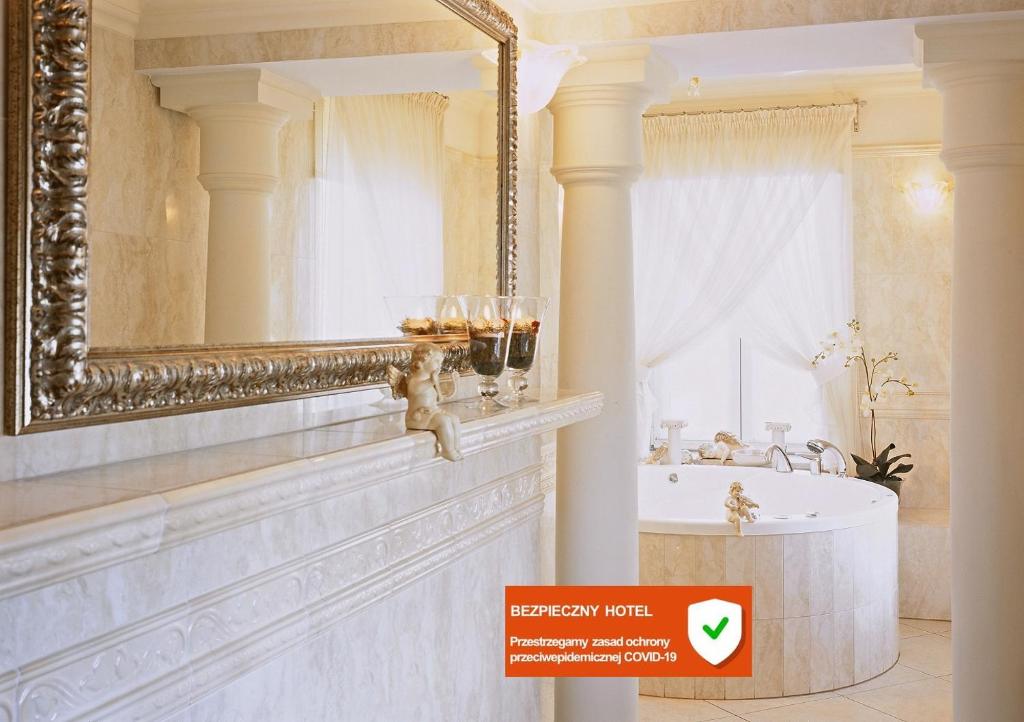 La salle de bains est pourvue d'un grand miroir et d'une baignoire. dans l'établissement Hotel Aleksander, à Włocławek