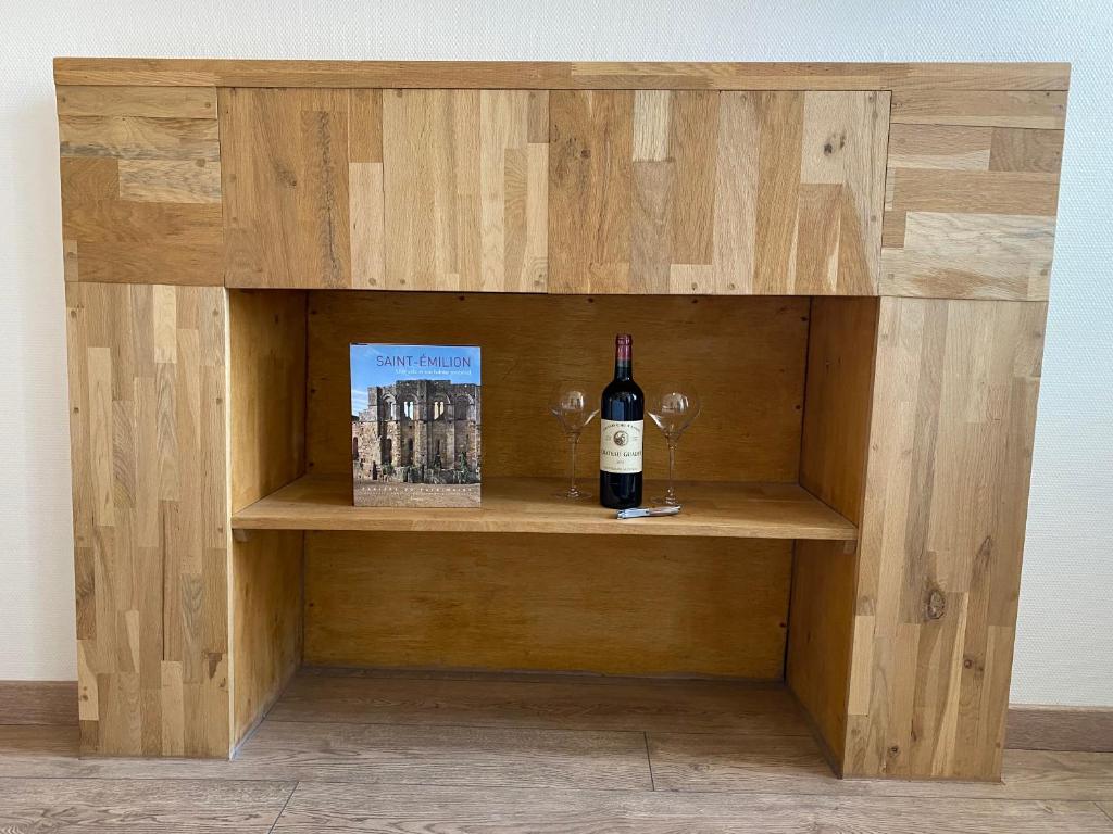 a wooden shelf with a bottle of wine and glasses at Logis des Jurats in Saint-Émilion