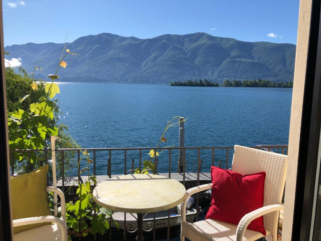 balcone con tavolo, sedie e vista sull'acqua di Apartments Posta al Lago a Ronco sopra Ascona