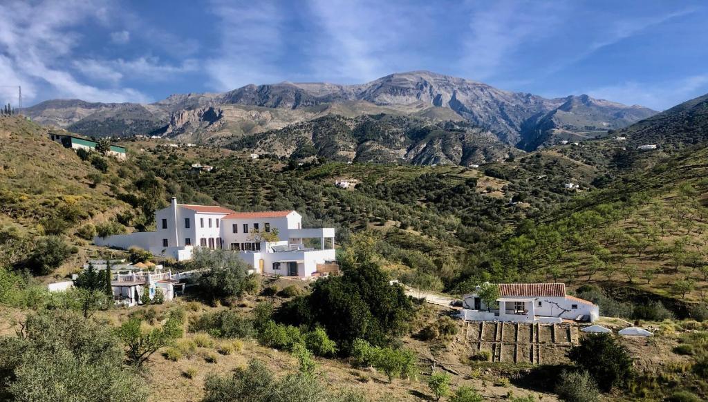 une maison sur une colline avec des montagnes en arrière-plan dans l'établissement Apartments Cortijo La Zapatera, à Canillas de Aceituno
