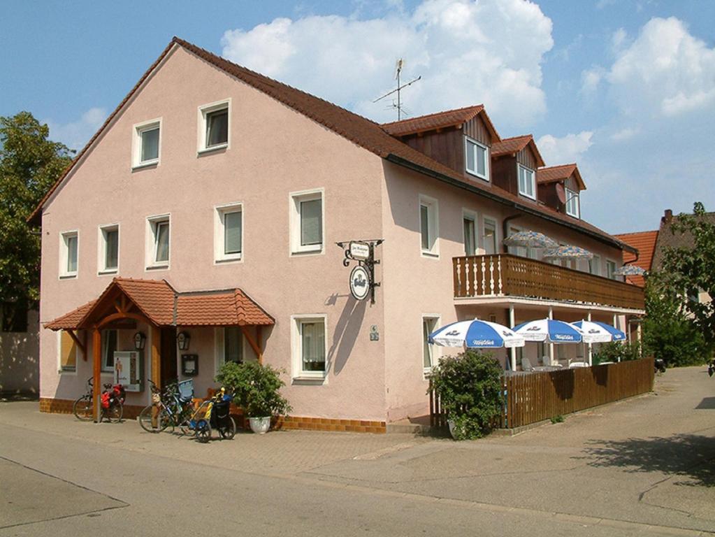 a large pink building with umbrellas in front of it at Landgasthaus Zum Mönchshof in Wolframs-Eschenbach