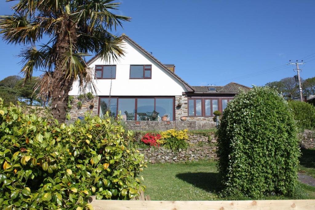 uma casa branca com uma palmeira e arbustos em Kerryanna Country House Bed and Breakfast em Mevagissey