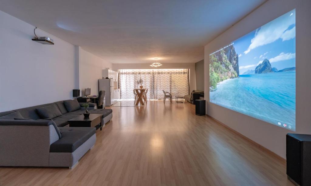 ein Wohnzimmer mit einem Großbild-TV an der Wand in der Unterkunft Cinema Zeus Studios - by Avelink in Spáta