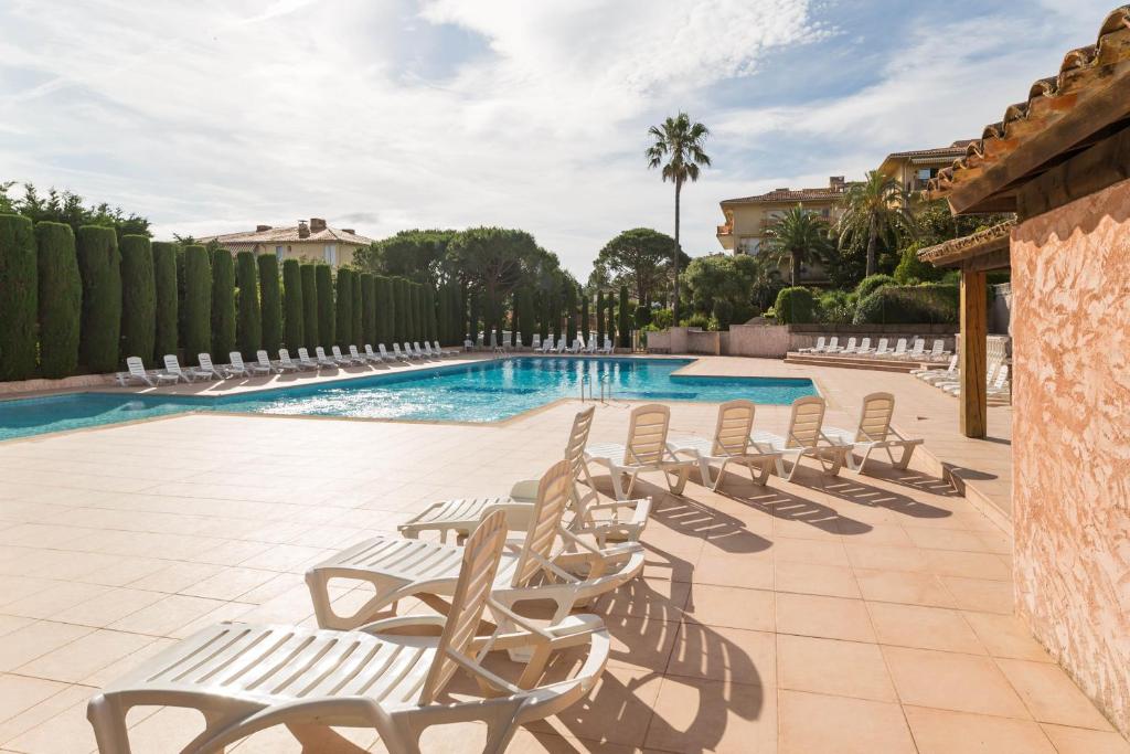 a row of lounge chairs next to a swimming pool at Résidence Pierre &amp; Vacances Eden Parc in Saint-Tropez
