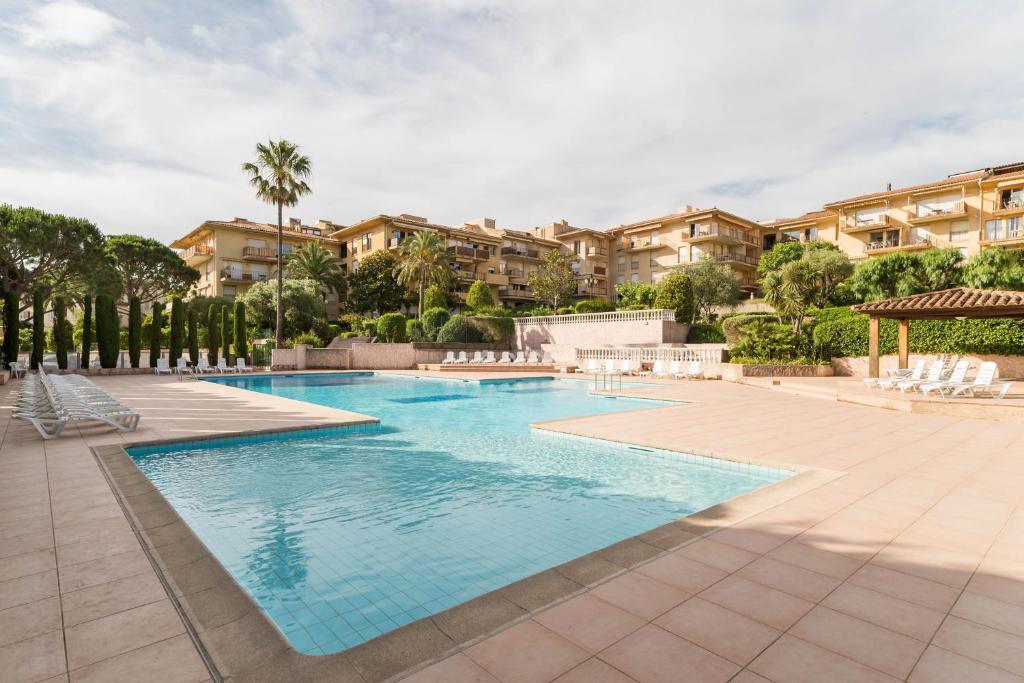 a swimming pool in a resort with palm trees and buildings at Résidence Pierre & Vacances Eden Parc in Saint-Tropez