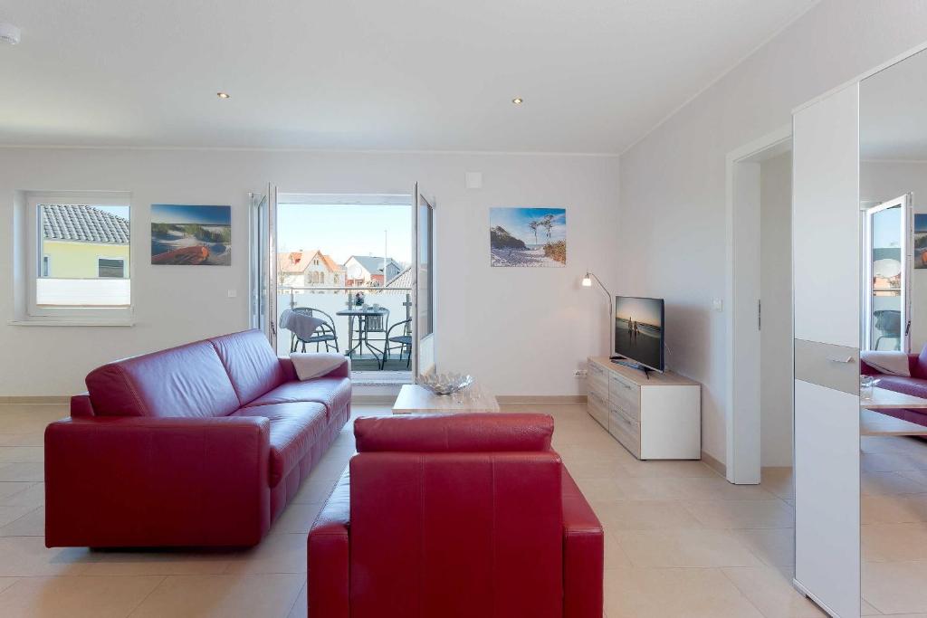 ein Wohnzimmer mit einem roten Sofa und einem TV in der Unterkunft Ferienwohnung Steuerbord in Zinnowitz