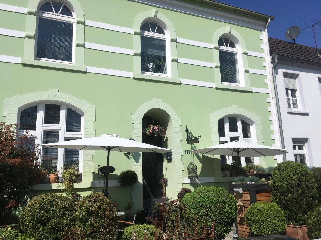 un edificio verde con dos sombrillas delante en Zweitheimat, en Kalkar