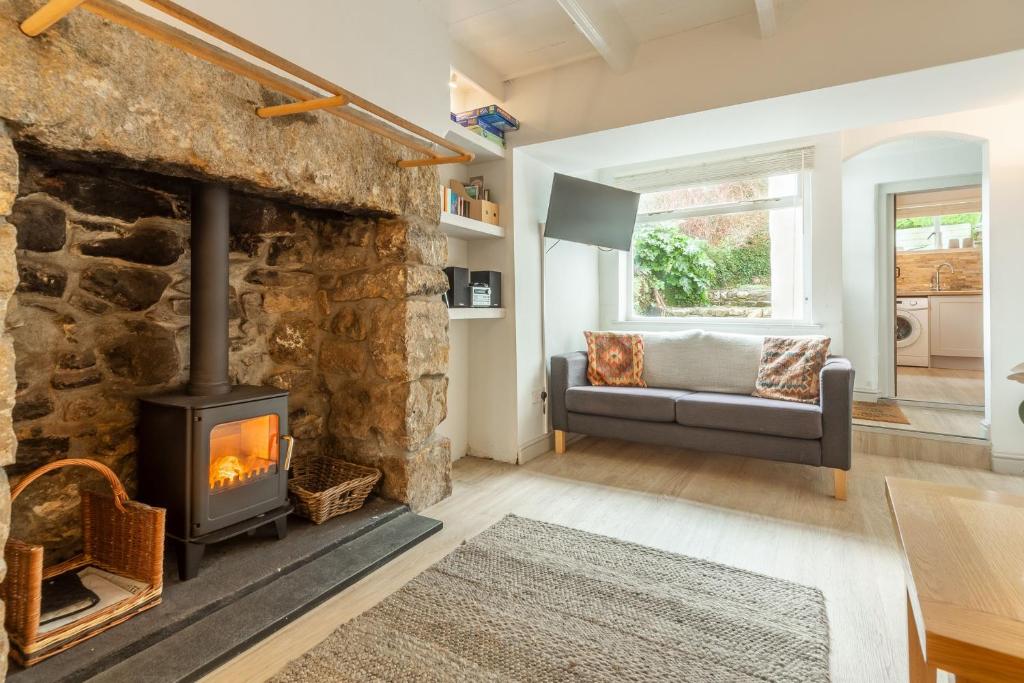 a living room with a stone fireplace and a couch at Porthgwidden Cottage in Uny Lelant