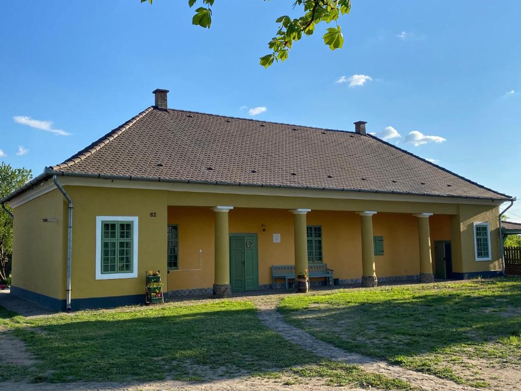 a small yellow house with a green door at Hengermalom Kúria in Szécsény