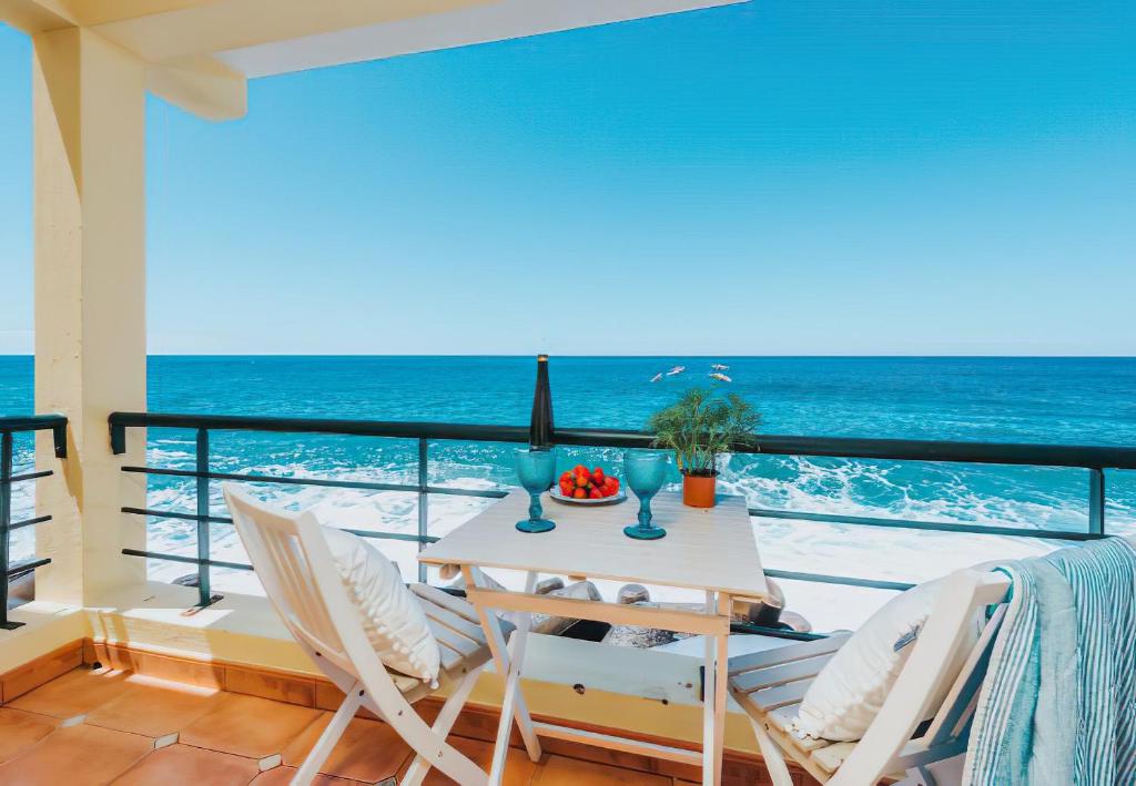 a balcony with a table and chairs and the ocean at The Yellow House in Paul do Mar