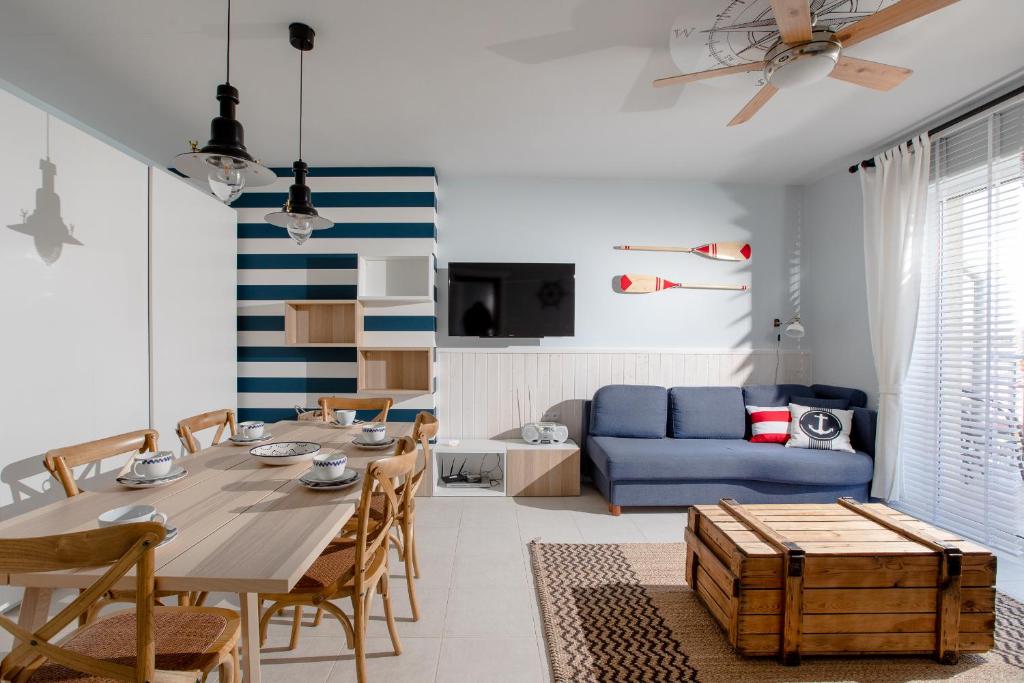 a living room with a table and a blue couch at Apartamenty Latarnia Morska – Sun Seasons 24 in Kołobrzeg