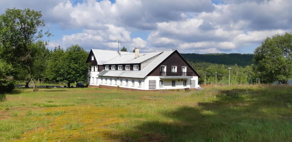 ein großes weißes Haus auf einem Grasfeld in der Unterkunft Chata na Souši in Desná