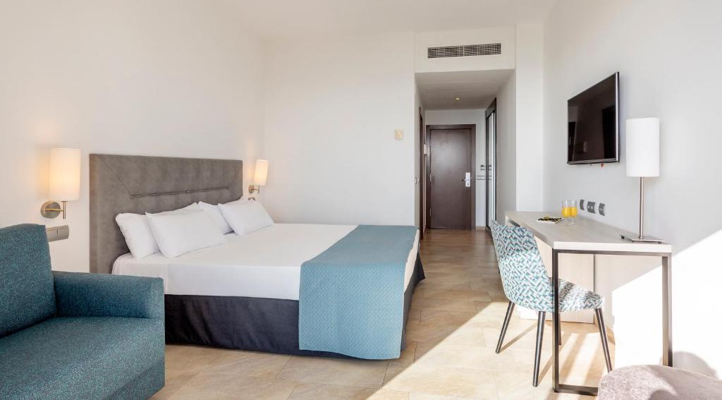 a bedroom with a bed and a chair and a table at Ilunion Calas de Conil in Conil de la Frontera
