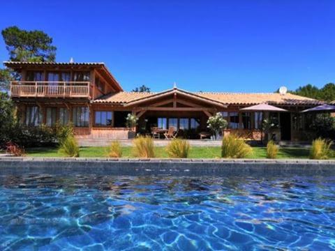a house with a swimming pool in front of it at La Maison Moutchic in Lacanau