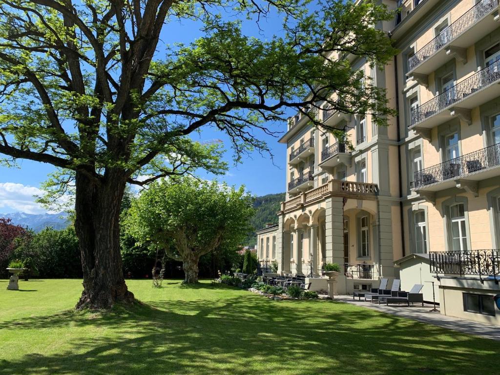 un gran edificio con un árbol delante en Parkhotel du Sauvage, en Meiringen