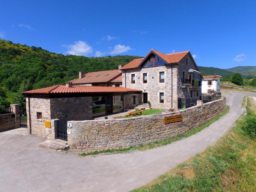 a large house with a stone wall next to a road at El Balcon De La Lomba in La Lomba