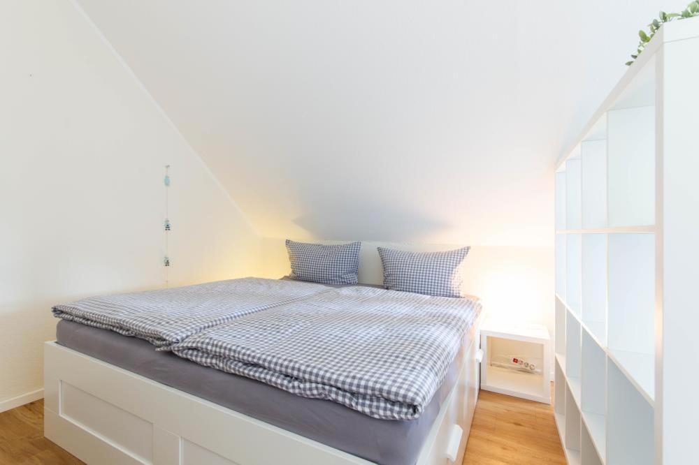 um quarto branco com uma cama com almofadas azuis em Ferienwohnung Ocean Lodge 2 em Haffkrug