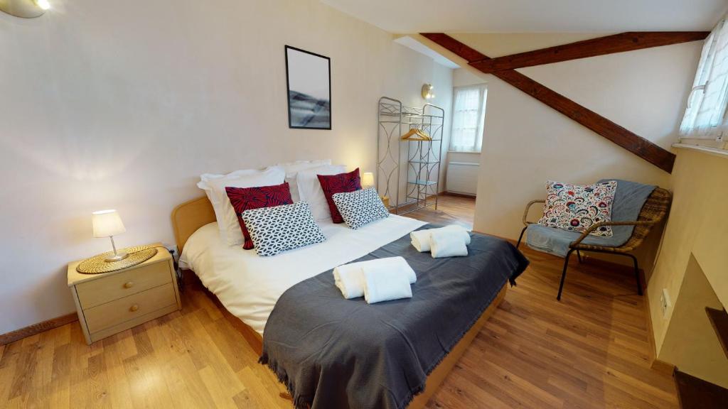 a bedroom with two beds and a chair at Aux Bijoux De Colmar - 1 Parking Gratuit in Colmar
