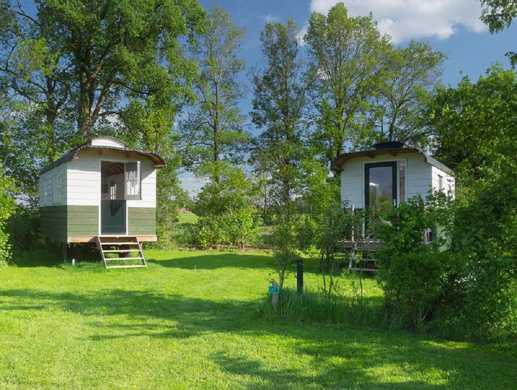 Deux mobile homes dans un champ d'herbe dans l'établissement B&B Pipowagen "het Wellnesst" op Wellness Camping en B&B Stoltenborg, à Meddoo