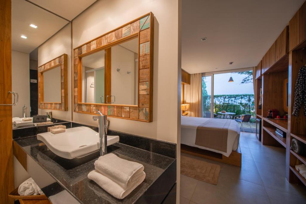 uma casa de banho com um lavatório e um quarto com uma cama em Hotel Spa Nau Royal em Camburi