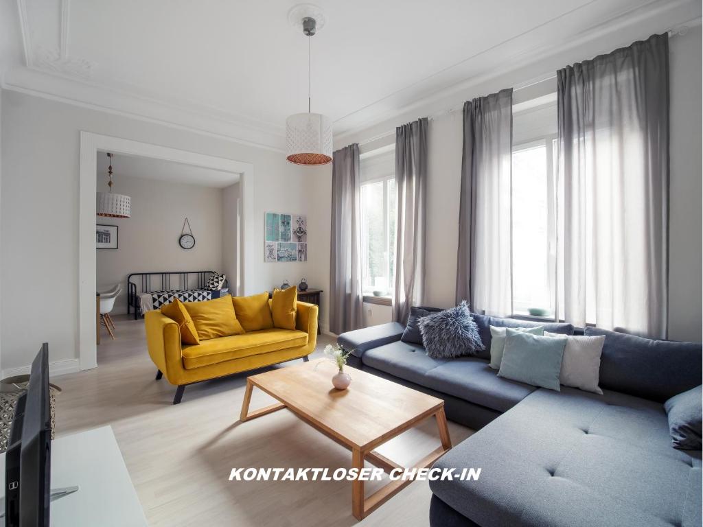 sala de estar con sofá azul y silla amarilla en City Apartments Siegburg, en Siegburg