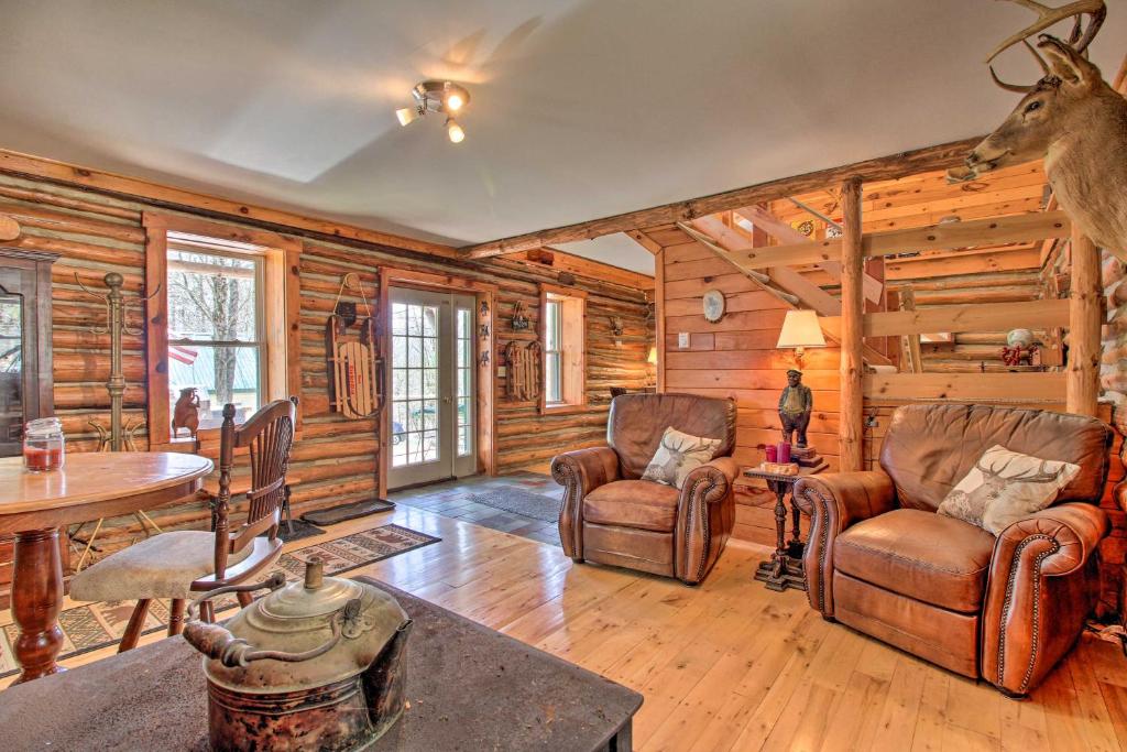 Cabaña de madera con sala de estar con sillas y mesa en Spacious Mtn Cabin on 7 Private Acres in Athol!, en Athol