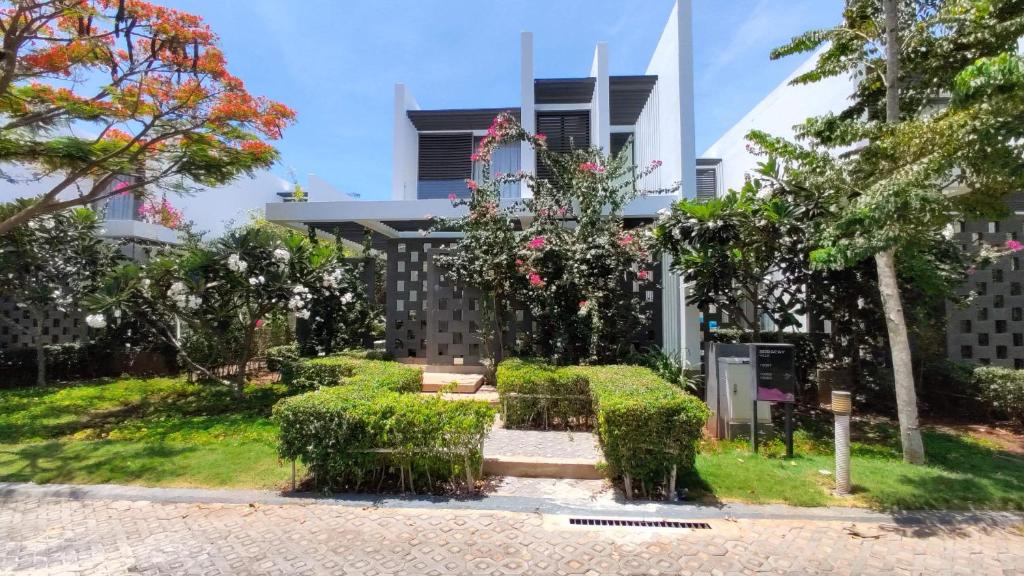 een gebouw met struiken en bloemen ervoor bij Oceanami Villas & Beach Club 3 bedroom villa in Long Hai