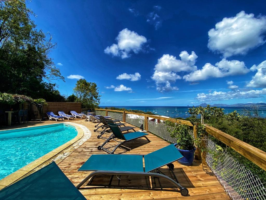 a swimming pool with lounge chairs and the ocean at Anoli Lodges in Sainte-Anne