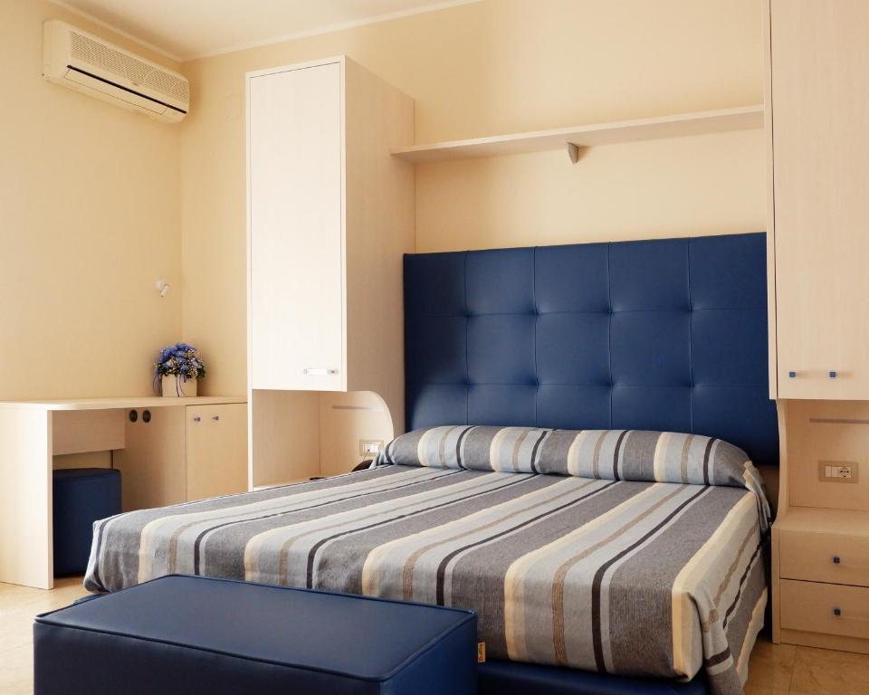 a bedroom with a blue bed with a blue headboard at Hotel Riviera in Porto San Giorgio