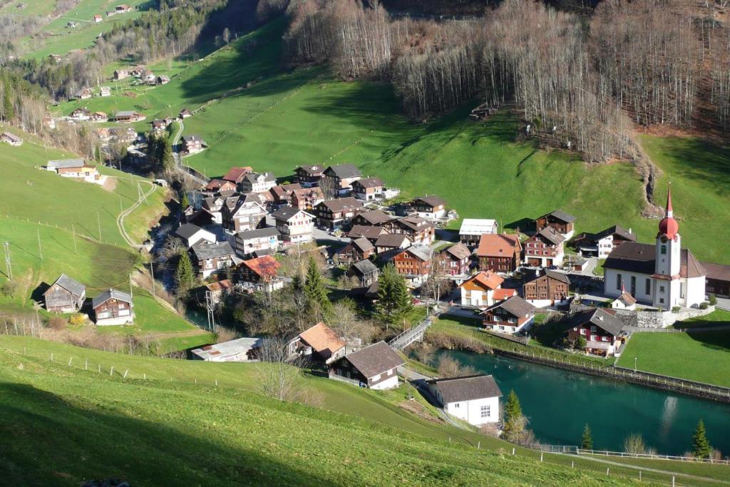 a village on a hill next to a river at Ferienwohnung ob Vierwaldsättersee in Isenthal