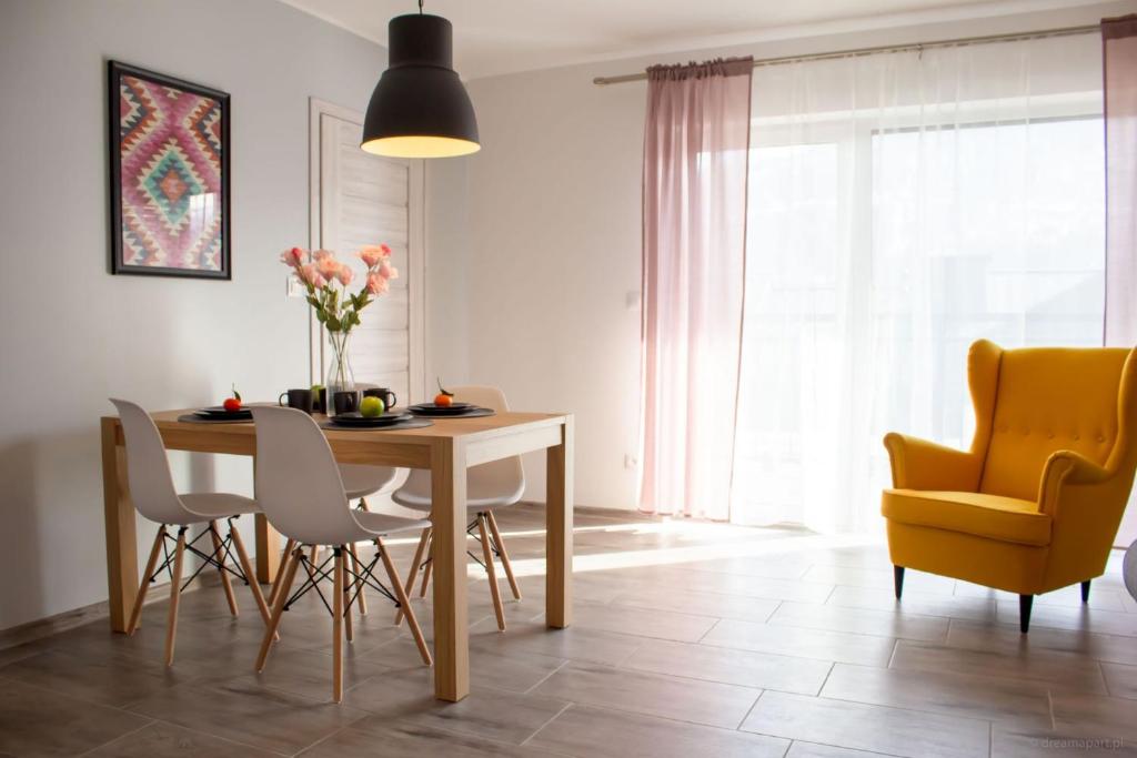 ein Esszimmer mit einem Tisch und einem gelben Stuhl in der Unterkunft Apartamenty JustRent Szczyrk in Szczyrk