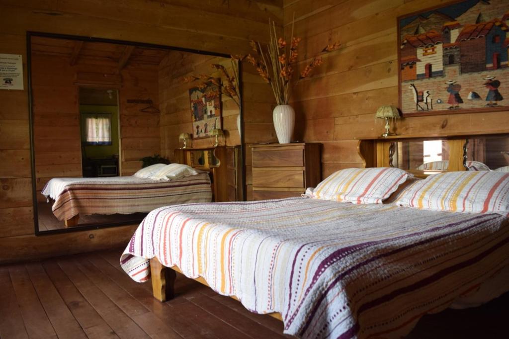 a bedroom with two beds in a log cabin at Hotel Chalets Los Volcanes in Alajuela