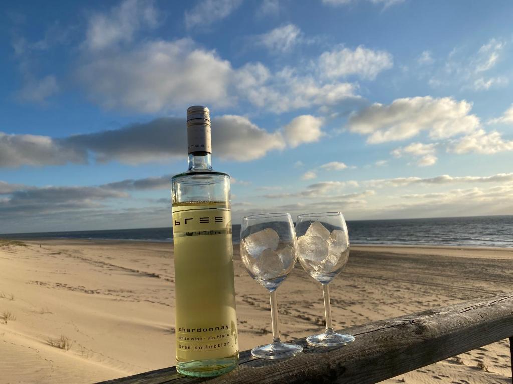 een fles wijn en twee glazen op het strand bij Dein Sylt in Westerland