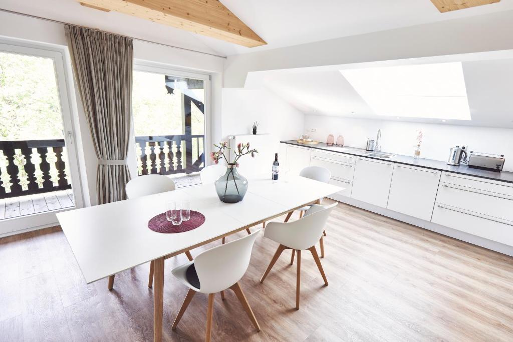 a kitchen and dining room with a white table and chairs at Sonnhof - Luxus Alpine Penthouse in Bad Wiessee