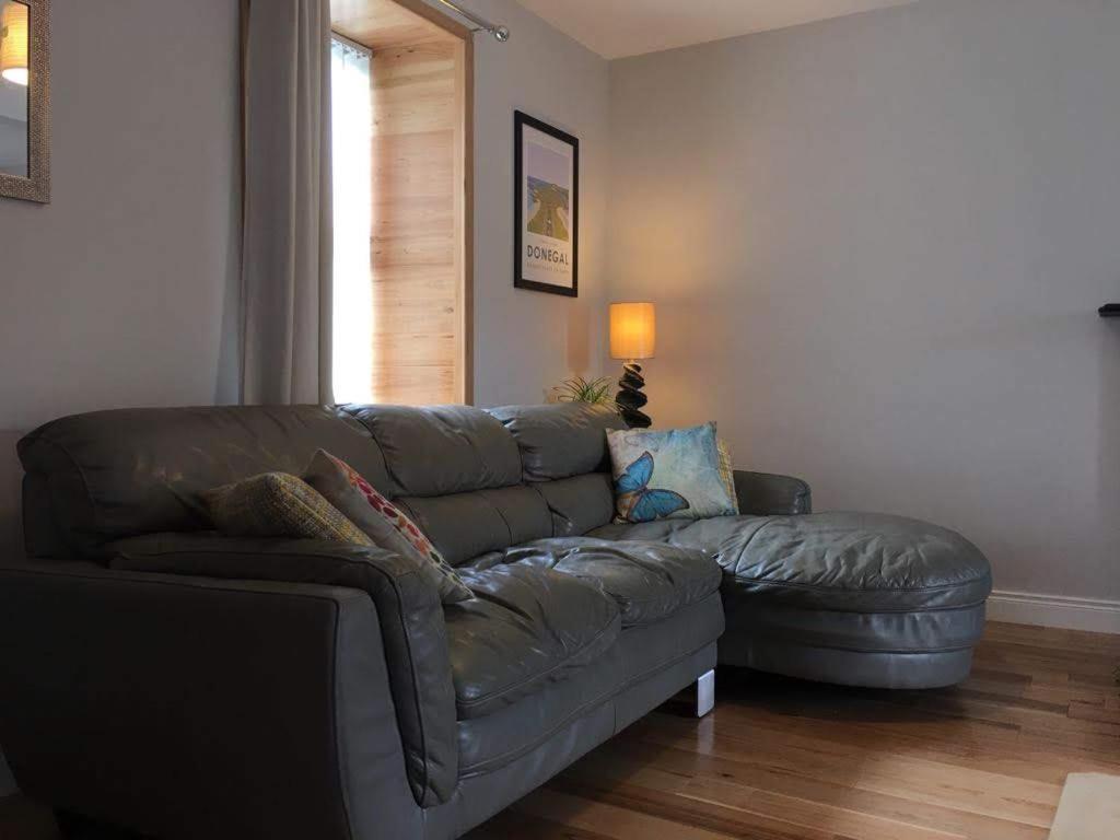 a living room with a leather couch and a window at Village Way Apartments in Kincasslagh