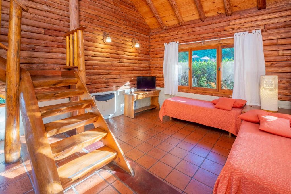 una sala de estar con una escalera en una cabaña de madera en Grenouille en Villa General Belgrano