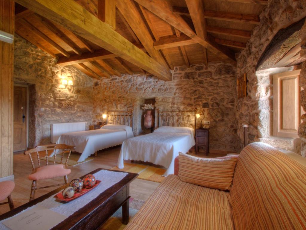 1 dormitorio con 2 camas en una habitación de piedra en Casa Baralló en Lobios