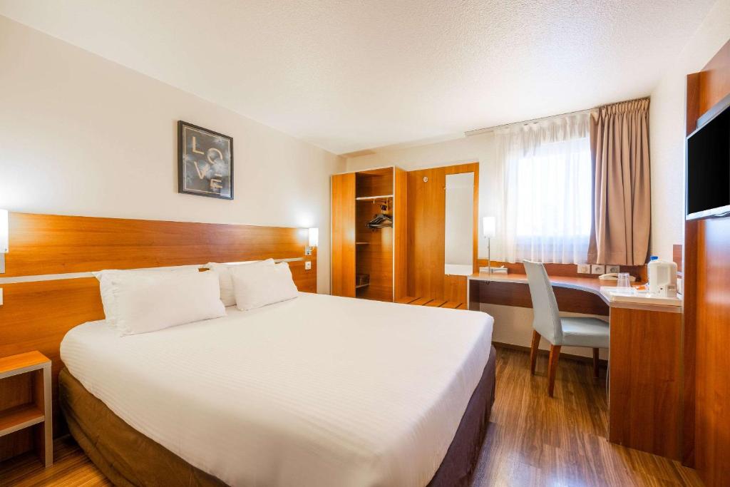 a hotel room with a large bed and a desk at Comfort Hotel Aeroport Lyon St Exupery in Saint-Exupéry