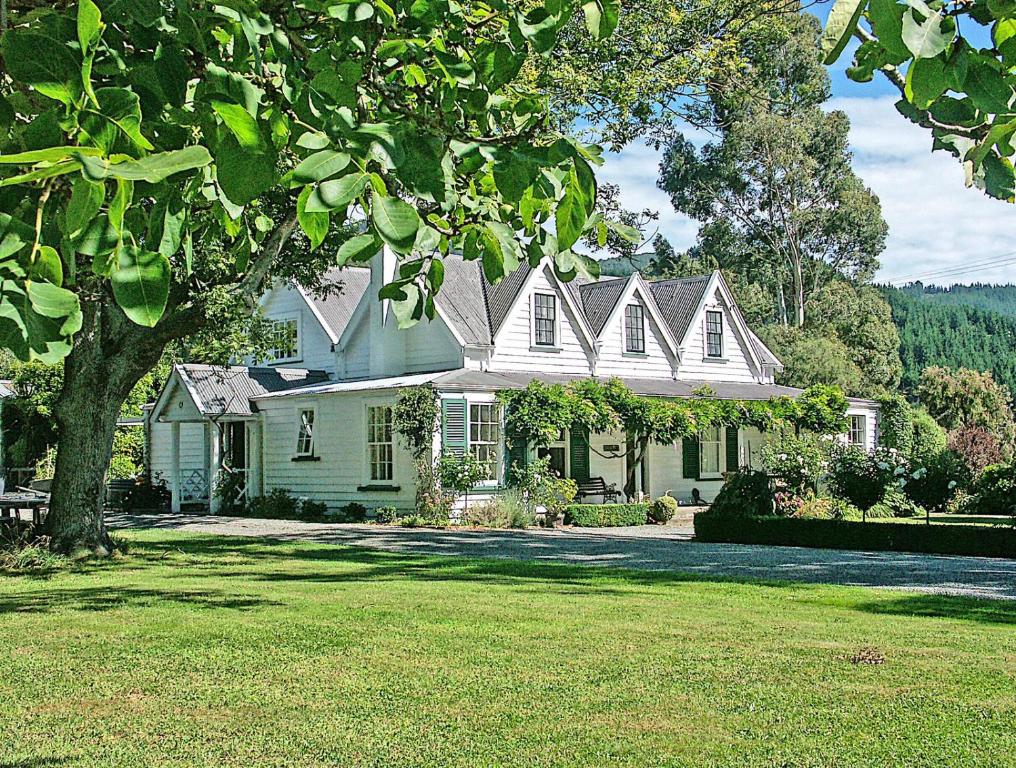 a white house with a tree in the yard at Marlborough B & B in Tuamarina