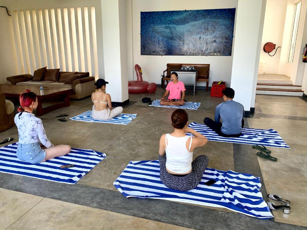 a group of people sitting on mats in a living room at Cardamon Hotel Nilaveli in Nilaveli
