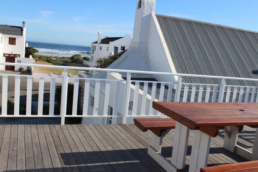 a wooden bench sitting on a balcony with the beach at Phoenix 1 in Paternoster
