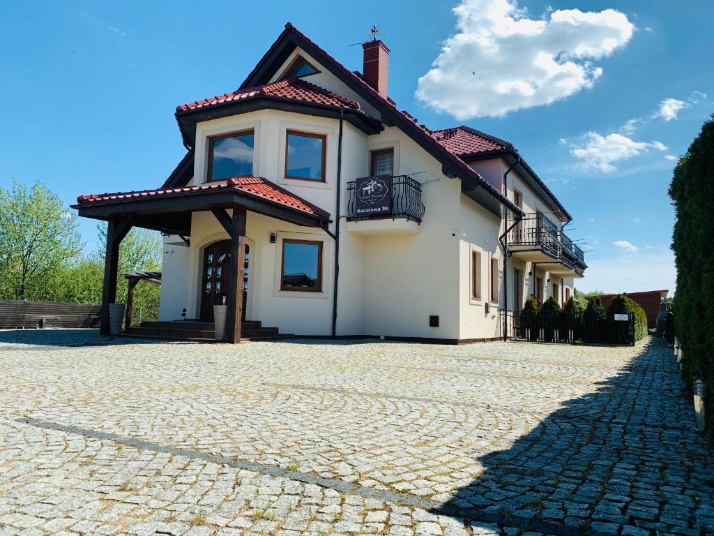 a white house with a cobblestone driveway at Stary Piernik in Grzybowo