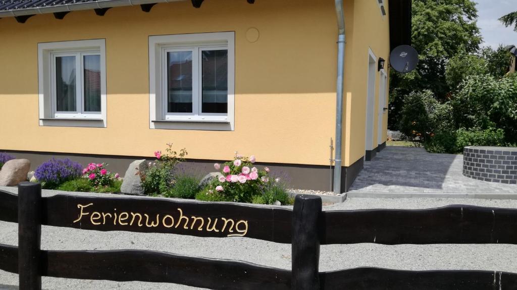 uma cerca em frente a uma casa com flores em Ferienwohnung Luba Lipa em Drachhausen
