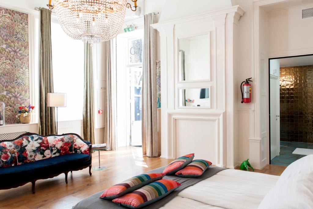 a bedroom with a bed and a couch and a chandelier at Boutique Hotel De Salon in The Hague